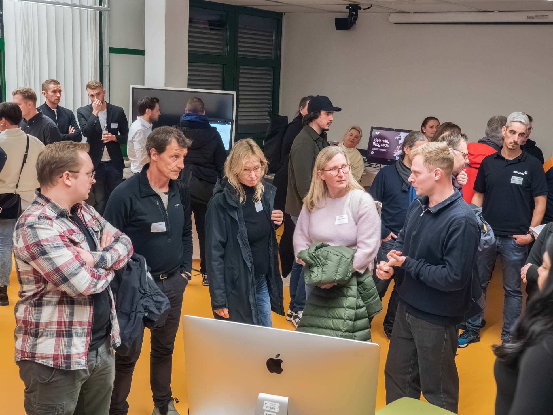 Eine Gruppe von Menschen steht um einen Bildschirm herum und diskutiert